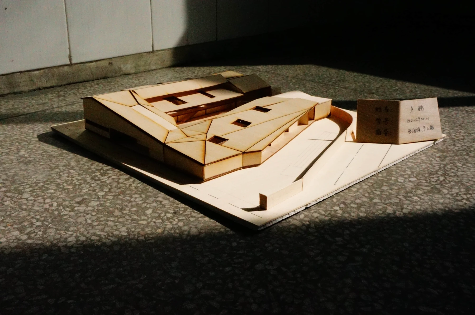 Low architectural model with angular roofs casting strong shadows in sunlight